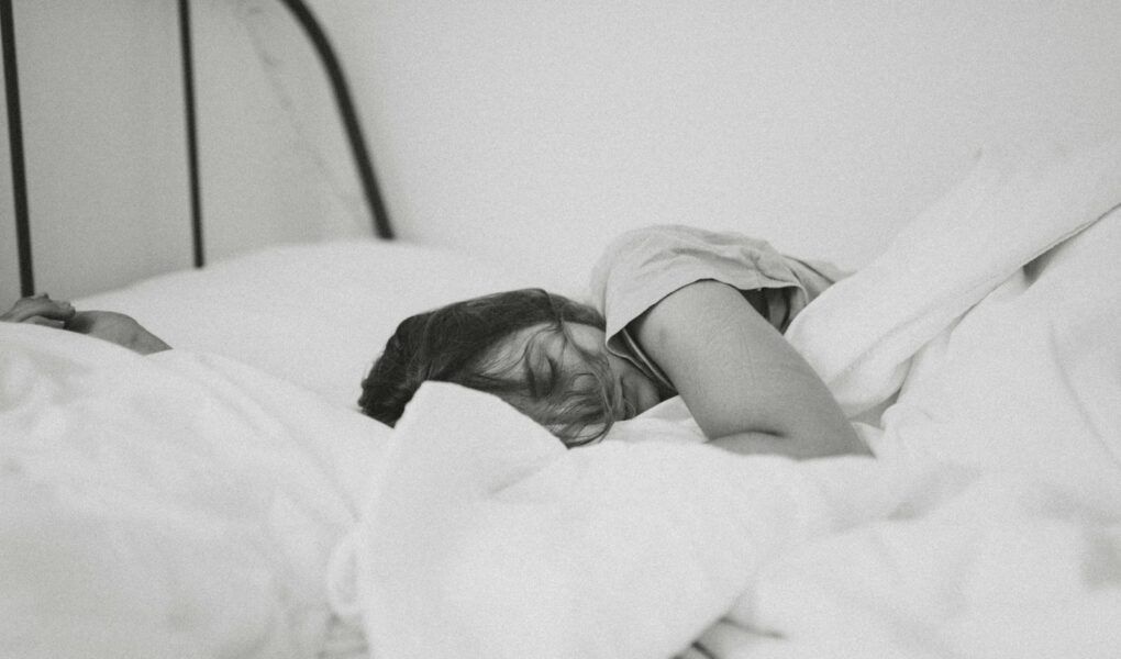 grayscale photo of sleeping woman lying on bed