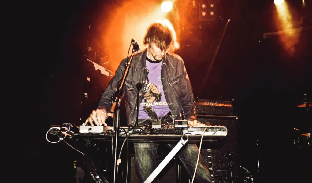Energetic performance of a synth player on stage during a live music concert.