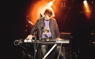 Energetic performance of a synth player on stage during a live music concert.