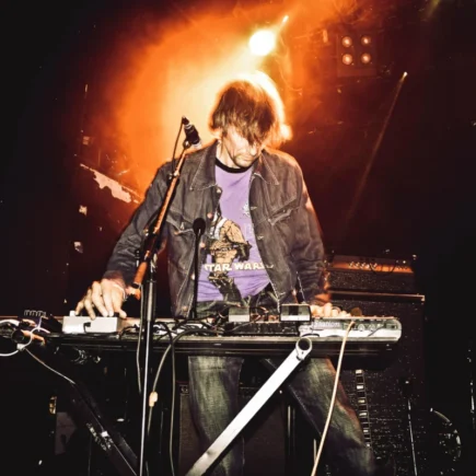 Energetic performance of a synth player on stage during a live music concert.