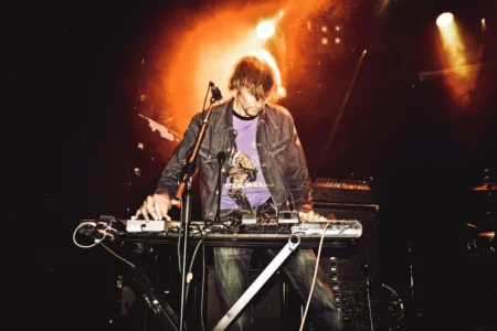 Energetic performance of a synth player on stage during a live music concert.